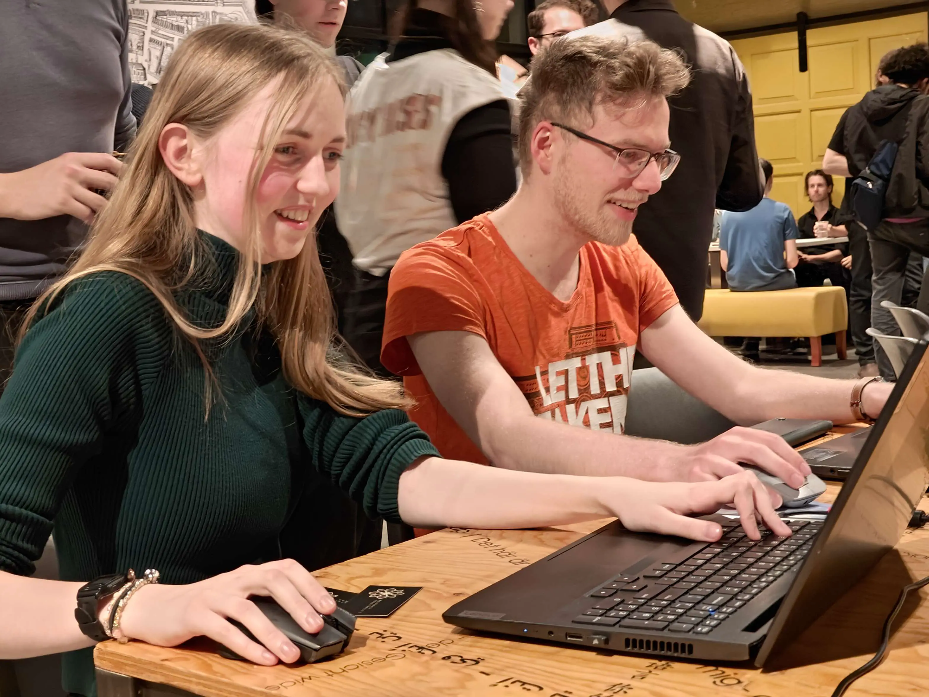 Photo taken during the Open Dev Mix, two people are playing behind laptops, both are smiling